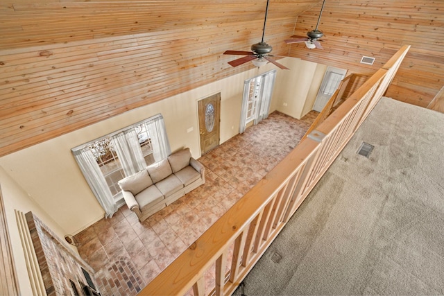 unfurnished living room featuring high vaulted ceiling, ceiling fan, wood ceiling, and carpet flooring