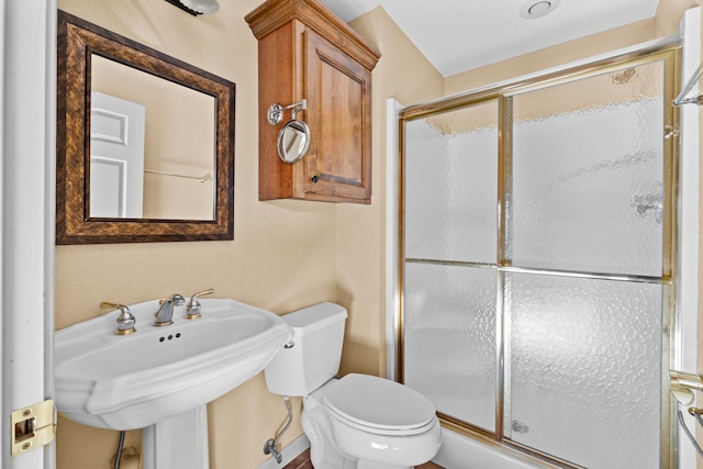 bathroom with toilet, a shower with door, and sink