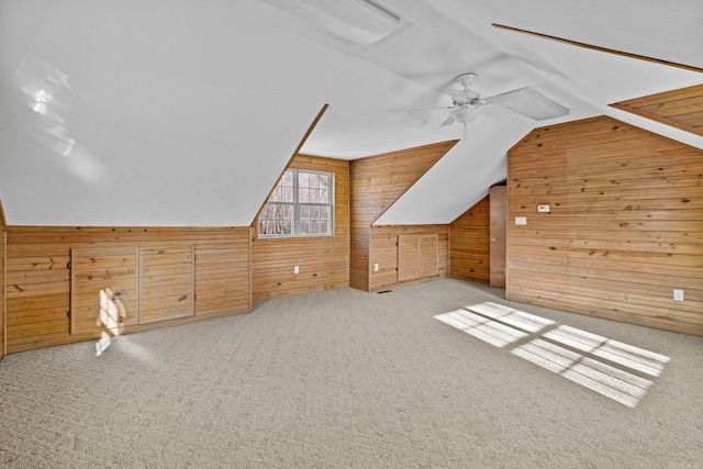 additional living space with vaulted ceiling, ceiling fan, light colored carpet, and wood walls