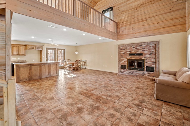 tiled living room with ceiling fan, wood ceiling, and a high ceiling