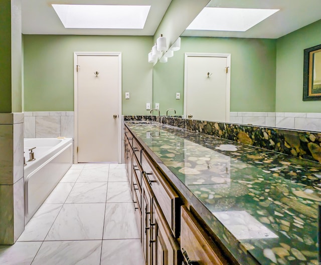 bathroom with vanity, a skylight, and a bathing tub