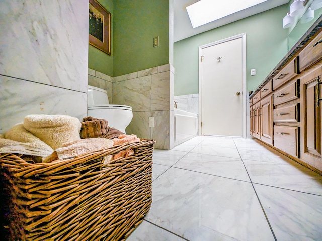 bathroom featuring a bathing tub, a skylight, and tile walls