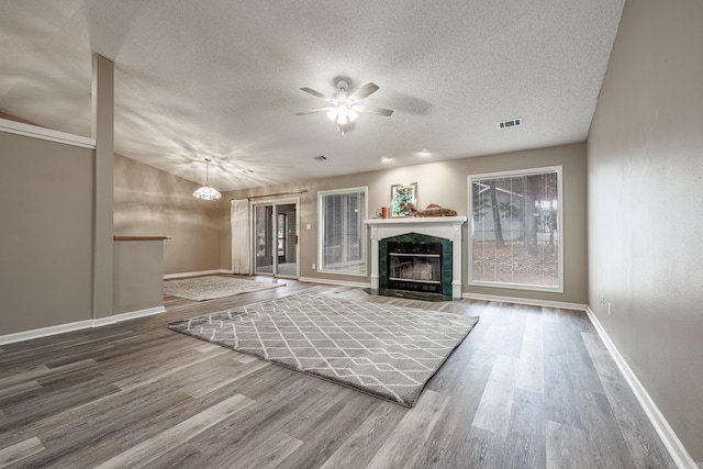 unfurnished living room featuring ceiling fan, wood-type flooring, a premium fireplace, and a textured ceiling