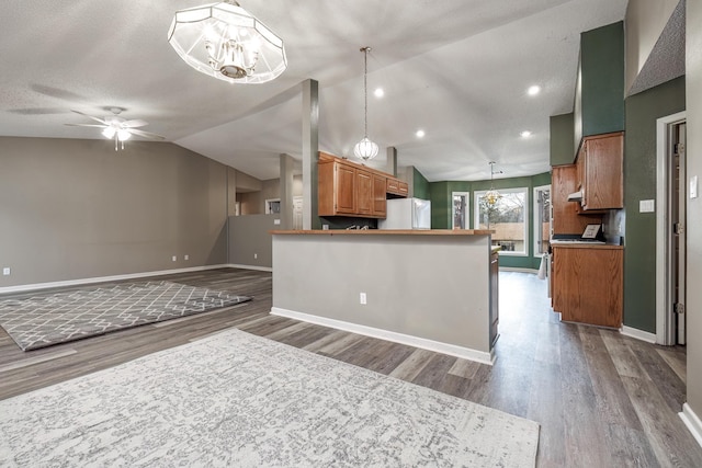 kitchen with hardwood / wood-style floors, decorative light fixtures, white appliances, lofted ceiling, and ceiling fan with notable chandelier