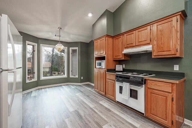 kitchen featuring decorative light fixtures, white appliances, a textured ceiling, and light hardwood / wood-style flooring