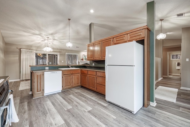 kitchen with hanging light fixtures, kitchen peninsula, sink, and white appliances