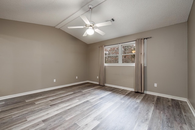 spare room featuring vaulted ceiling, ceiling fan, a textured ceiling, and light wood-type flooring