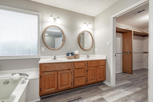 bathroom with a tub, a textured ceiling, vanity, and hardwood / wood-style floors