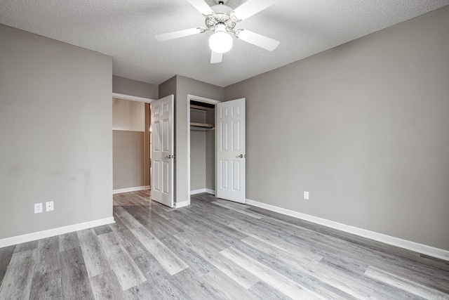 unfurnished bedroom featuring ceiling fan, light wood-type flooring, a closet, and a textured ceiling