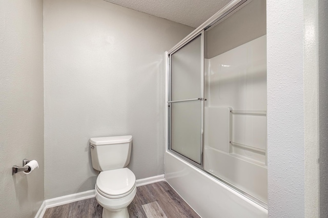 bathroom featuring toilet, shower / bath combination with glass door, a textured ceiling, and hardwood / wood-style floors