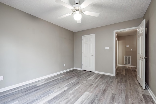 unfurnished bedroom featuring ceiling fan, light hardwood / wood-style floors, a textured ceiling, and a closet