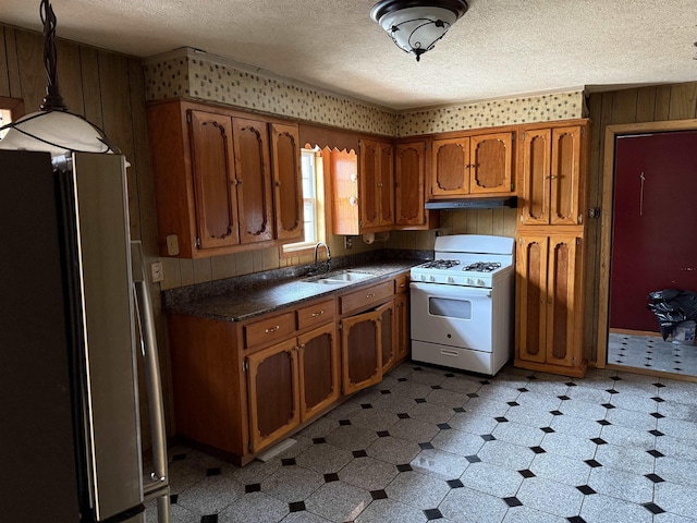 kitchen featuring sink, hanging light fixtures, white range with gas stovetop, a textured ceiling, and stainless steel fridge