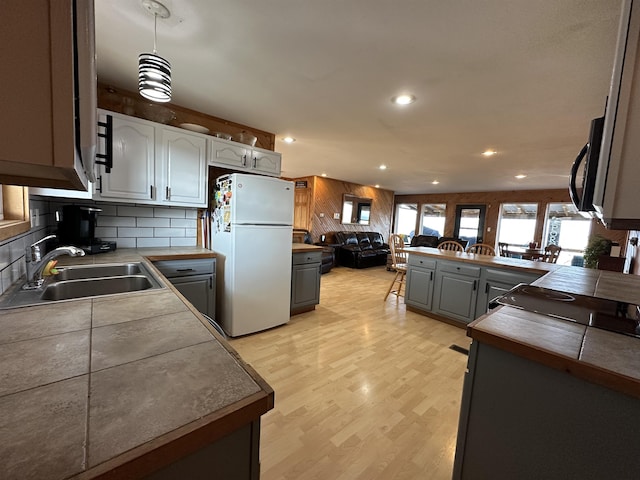 kitchen with white refrigerator, sink, hanging light fixtures, gray cabinets, and kitchen peninsula