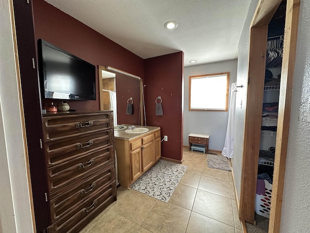 bathroom with a textured ceiling, tile patterned flooring, and vanity