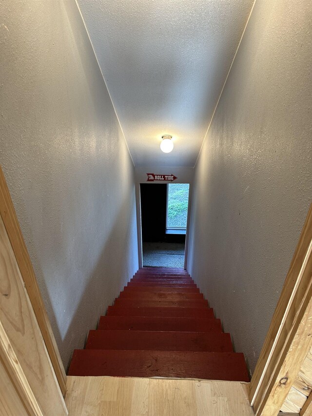 stairs with a textured ceiling and hardwood / wood-style floors