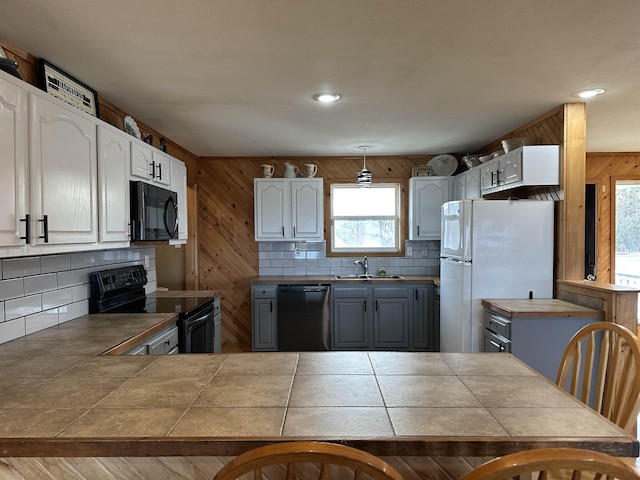 kitchen with tile counters, decorative light fixtures, black appliances, white cabinets, and sink