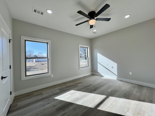 unfurnished room with ceiling fan, dark wood-type flooring, and plenty of natural light