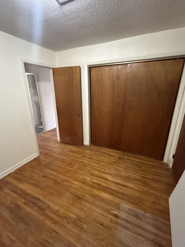 unfurnished bedroom featuring a textured ceiling, a closet, and dark hardwood / wood-style flooring