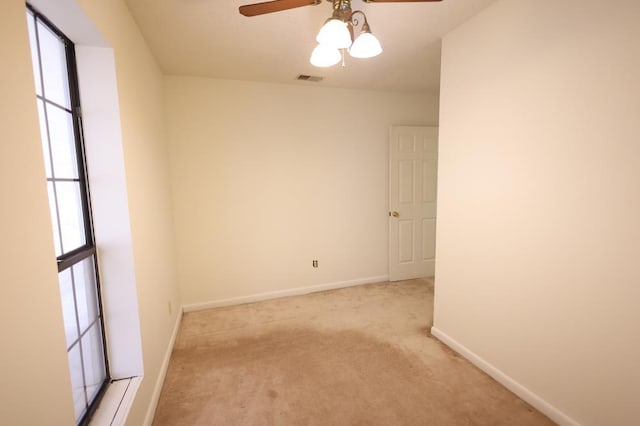 carpeted spare room featuring ceiling fan and plenty of natural light