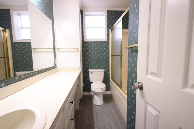 full bathroom with toilet, vanity, combined bath / shower with glass door, wood-type flooring, and ornamental molding