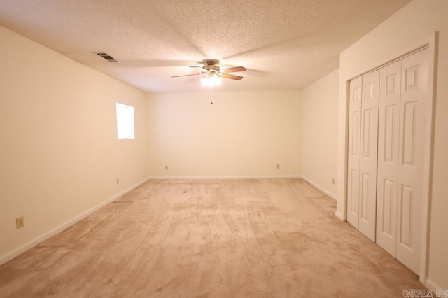 unfurnished bedroom with light carpet, ceiling fan, and a textured ceiling