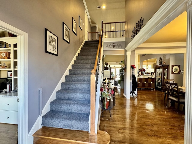 staircase with ornamental molding and wood-type flooring