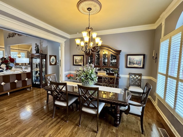 dining room featuring decorative columns, dark hardwood / wood-style floors, crown molding, and a chandelier