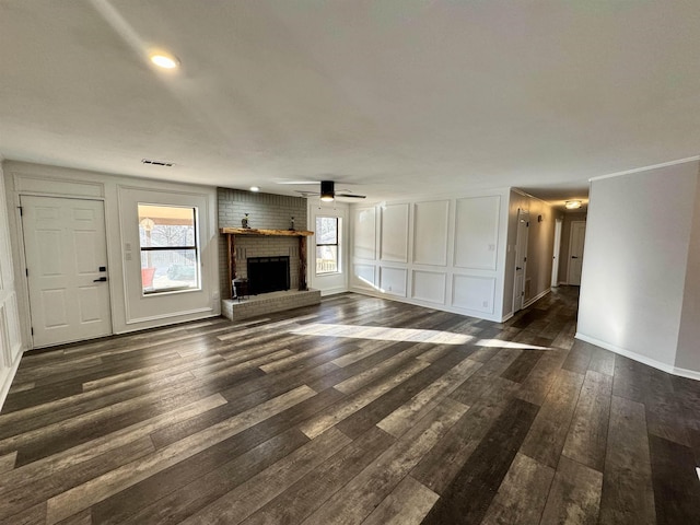 unfurnished living room with ceiling fan, a brick fireplace, and dark hardwood / wood-style flooring