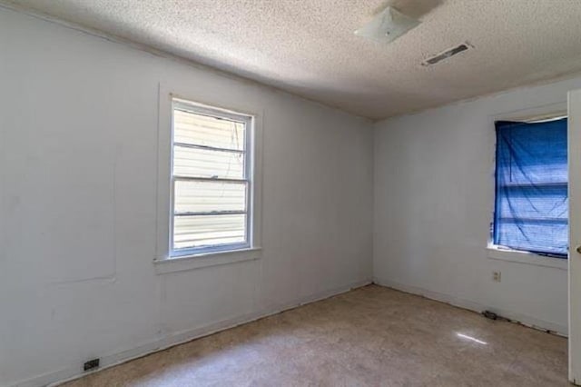 carpeted empty room with a textured ceiling