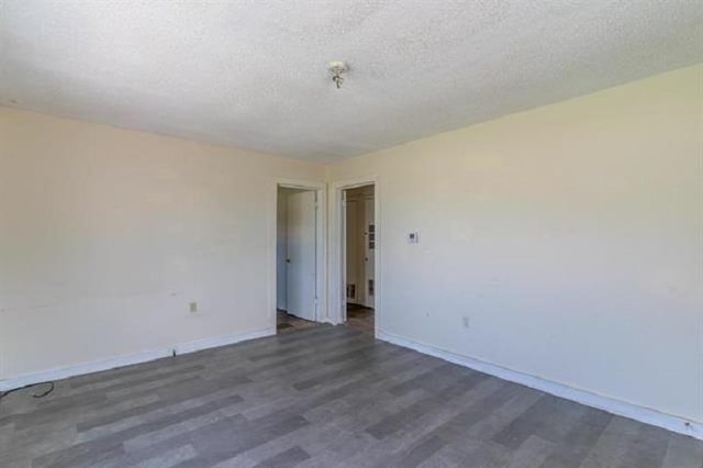empty room featuring a textured ceiling and dark hardwood / wood-style flooring