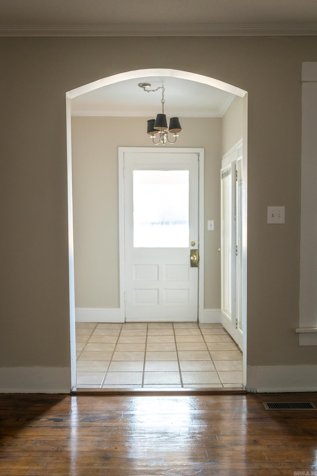 entryway featuring a chandelier, a healthy amount of sunlight, ornamental molding, and hardwood / wood-style flooring