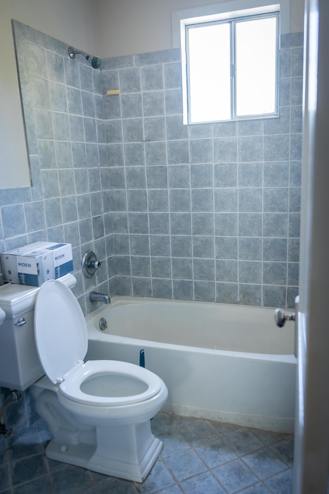 bathroom with toilet, tiled shower / bath, and tile walls