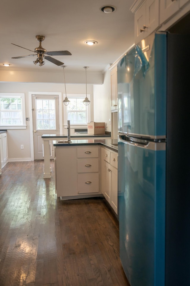 kitchen featuring ceiling fan, fridge, white cabinetry, hanging light fixtures, and dark hardwood / wood-style flooring