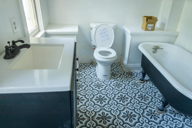 bathroom with a washtub, toilet, and sink