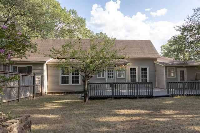 rear view of house featuring a wooden deck and a lawn