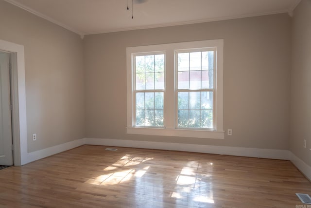 spare room featuring crown molding and light wood-type flooring