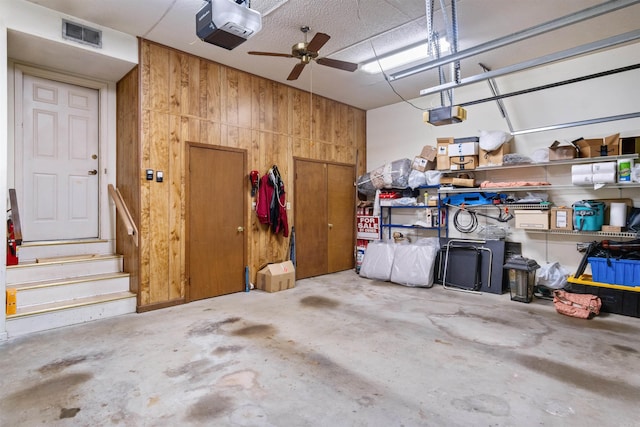 garage with ceiling fan, a garage door opener, and wooden walls