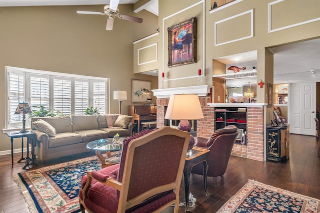 living room featuring a brick fireplace, ceiling fan, dark hardwood / wood-style floors, high vaulted ceiling, and beamed ceiling