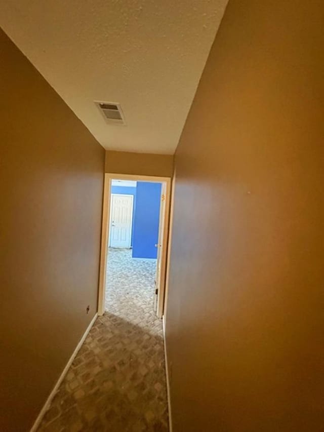 corridor with light carpet, a textured ceiling, and vaulted ceiling