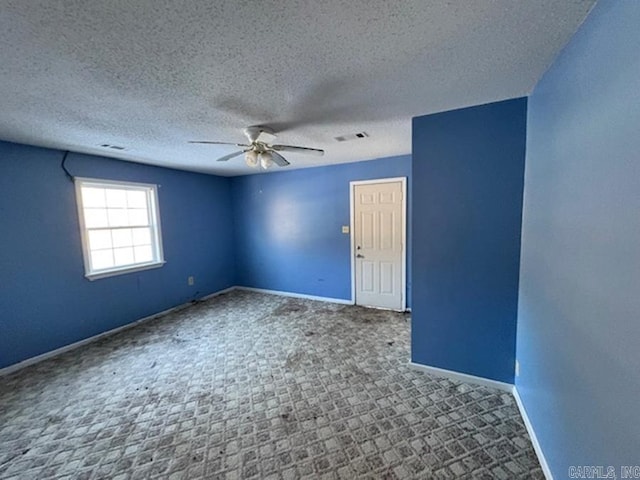 carpeted empty room with ceiling fan and a textured ceiling