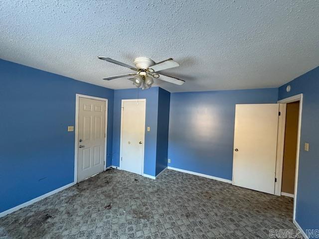 unfurnished bedroom with ceiling fan, dark carpet, and a textured ceiling