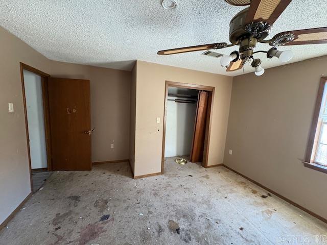 unfurnished bedroom with a textured ceiling, ceiling fan, and a closet