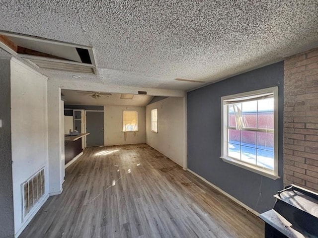 unfurnished living room with a healthy amount of sunlight, wood-type flooring, and a textured ceiling