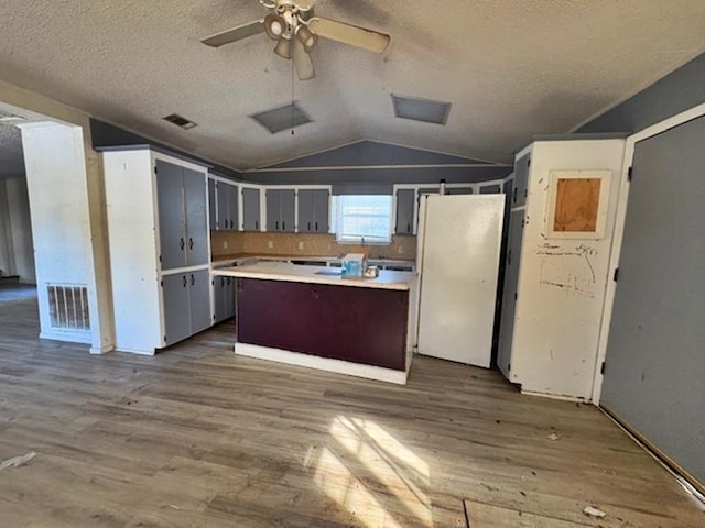 kitchen with vaulted ceiling, a kitchen island, hardwood / wood-style flooring, and white fridge