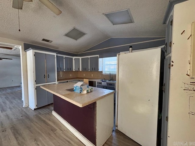 kitchen featuring ceiling fan, vaulted ceiling, dark hardwood / wood-style floors, gray cabinets, and a kitchen island