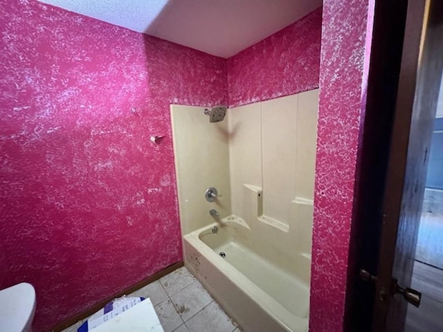 bathroom with toilet, tile patterned flooring, and washtub / shower combination