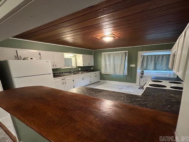 kitchen featuring white fridge, wood ceiling, white cabinets, and sink