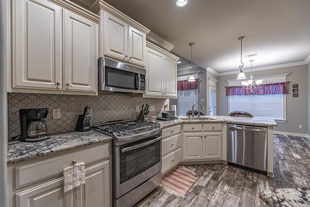 kitchen with kitchen peninsula, appliances with stainless steel finishes, dark hardwood / wood-style floors, decorative light fixtures, and sink