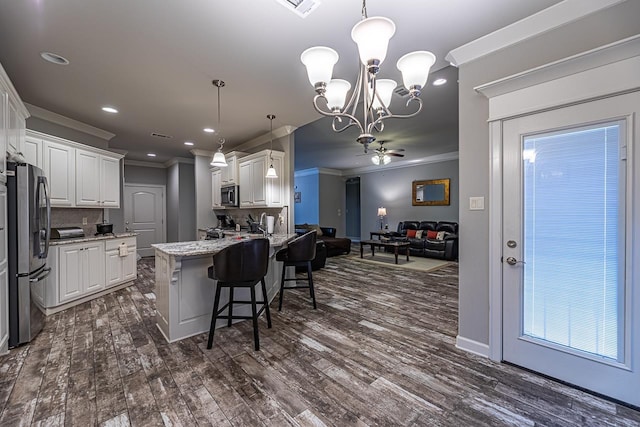 kitchen with pendant lighting, ornamental molding, stainless steel appliances, white cabinets, and ceiling fan with notable chandelier