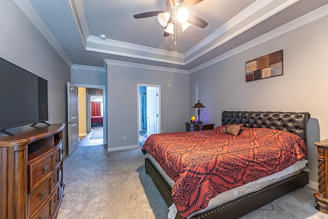 carpeted bedroom featuring a raised ceiling, ensuite bath, ceiling fan, and ornamental molding